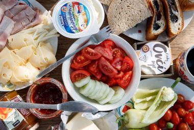 Delicious breakfast setup with cheese, cold cuts, bread, and fresh vegetables.